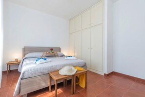Um quarto com cama, mesa de cabeceira e guarda-roupa.