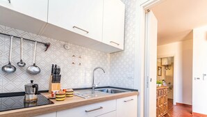 A modern kitchen with white cabinets, a black countertop, and a stainless steel sink. - Una Finestra Sul Porto, Alghero, Italy (Alghero)