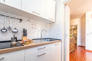 Een moderne keuken met witte kasten, een zwart aanrecht en een RVS spoelbak.