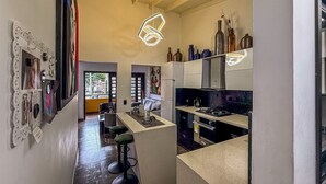 Una cocina moderna con una isla central, un comedor con taburetes de bar y vistas al exterior.