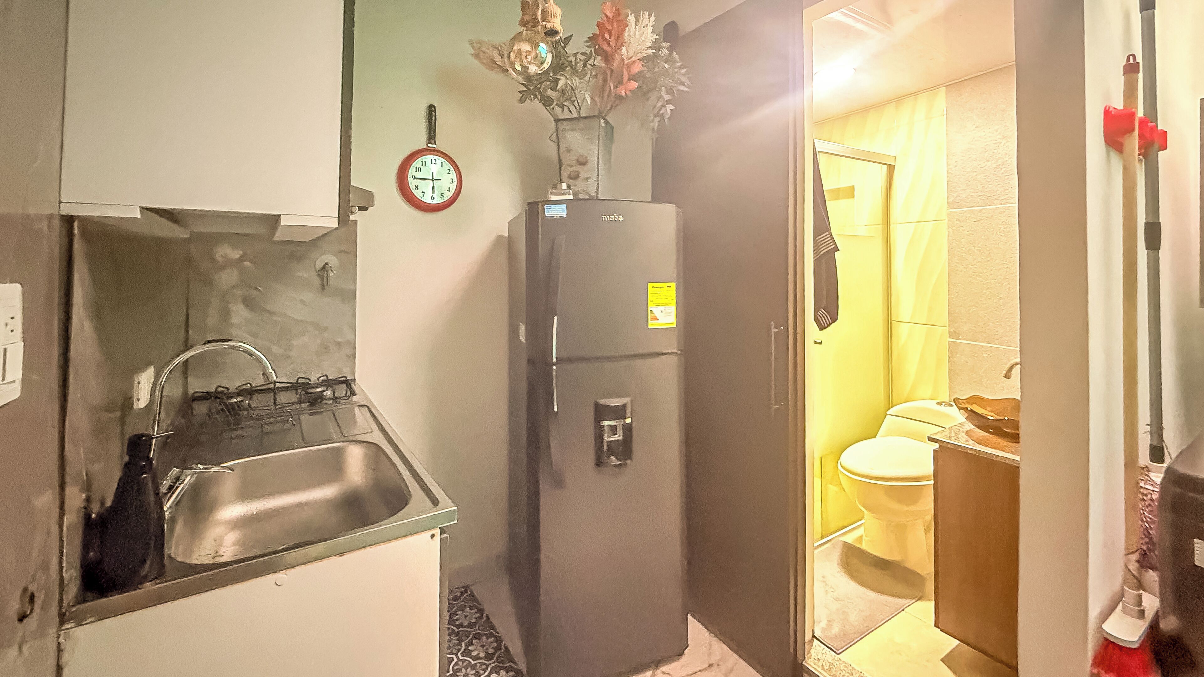 A compact kitchen with a sink, a refrigerator, and a small window.