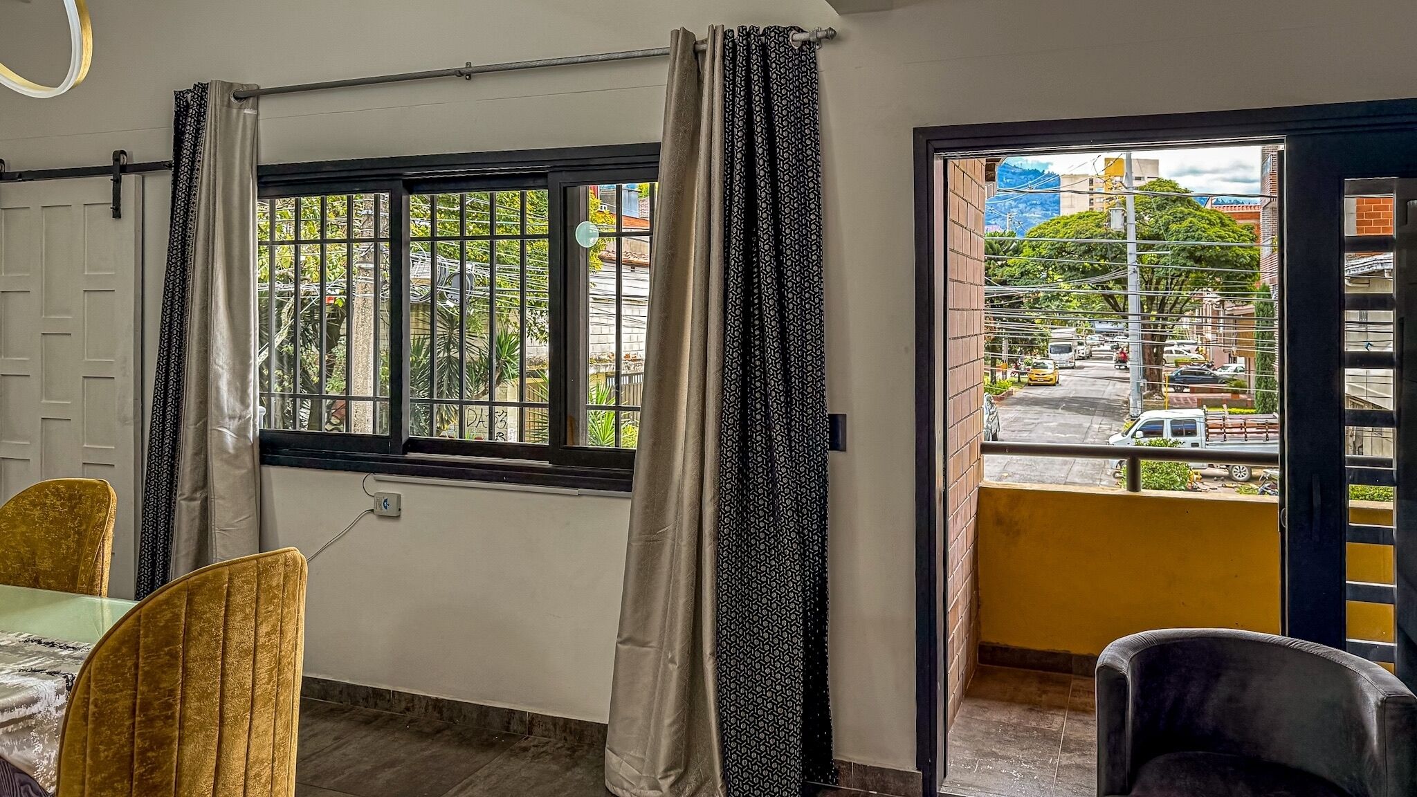 Une pièce avec une fenêtre donnant sur la rue, une porte et une table avec des chaises.