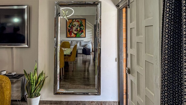 Un interior moderno con un espejo grande, una zona de comedor y un sofá.