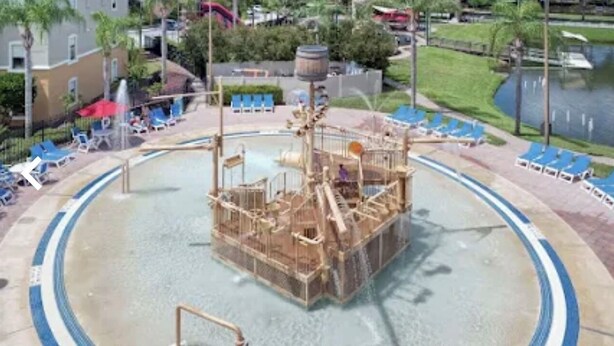 A water park with a central play structure, surrounded by blue lounge chairs and a pool. - 3 Free Disney tix! Charming ADA 2-bedroom villa 6 mi. from Disney @ Summer Bay (Clermont)