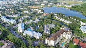 An aerial view of a residential area with houses, a swimming pool, and a lake. - 3 Free Disney tix! Charming ADA 2-bedroom villa 6 mi. from Disney @ Summer Bay (Clermont)