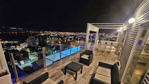 En takterrass med pool, utomhusmöbler och utsikt över staden.