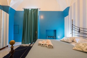 A hotel room with a bed, a window with curtains, and a metal bed frame.