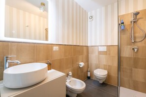 Un baño con un espejo grande, un lavamanos, un bidé y una ducha.