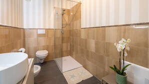 A modern bathroom with a glass-enclosed shower, a white toilet, and a large white sink.