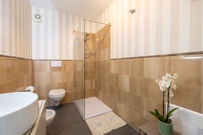 A modern bathroom with a glass-enclosed shower, a white toilet, and a large white sink.