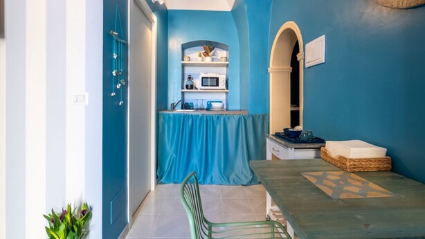 A compact kitchen with a blue wall, a microwave, and a sink.