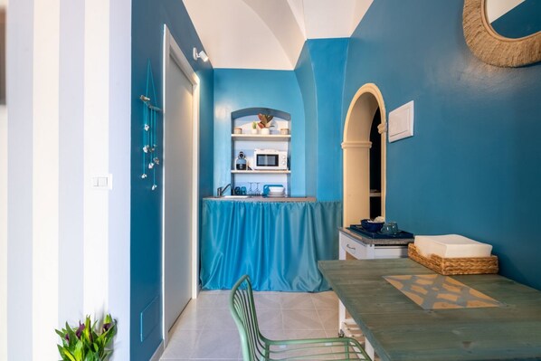 A compact kitchen with a blue wall, a microwave, and a sink.