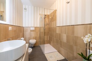 Un baño moderno con una bañera independiente, una ducha con mampara de vidrio y un inodoro.