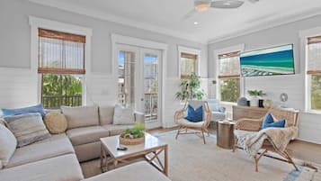 A spacious living room with a sofa, chairs, a coffee table, and a television.