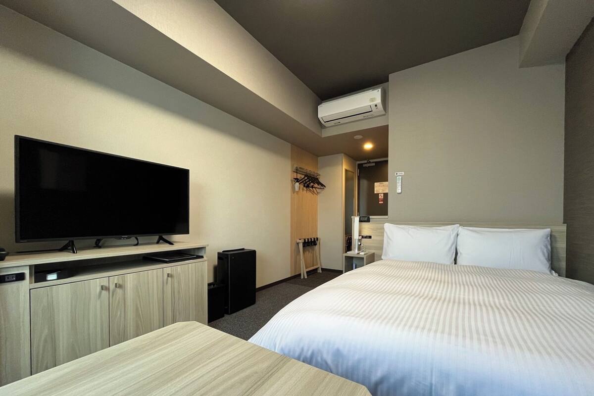 A hotel room with a bed, a TV, a desk, and a wardrobe.