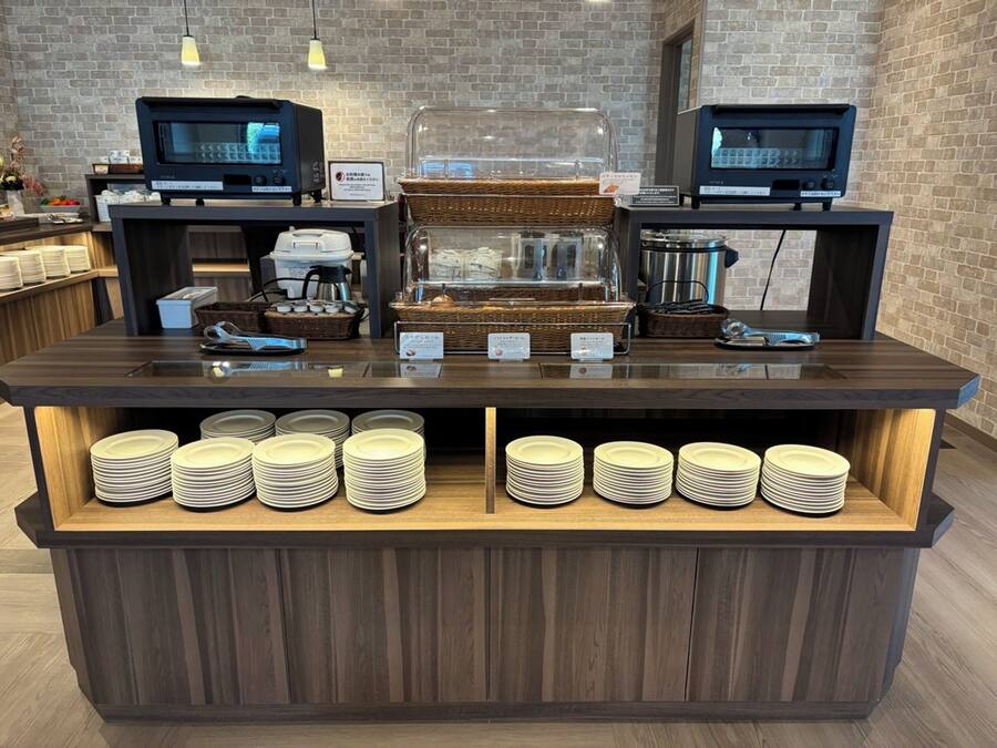 Ein Buffet mit zwei digitalen Menütafeln, einer Kaffeemaschine und gestapelten Tellern.