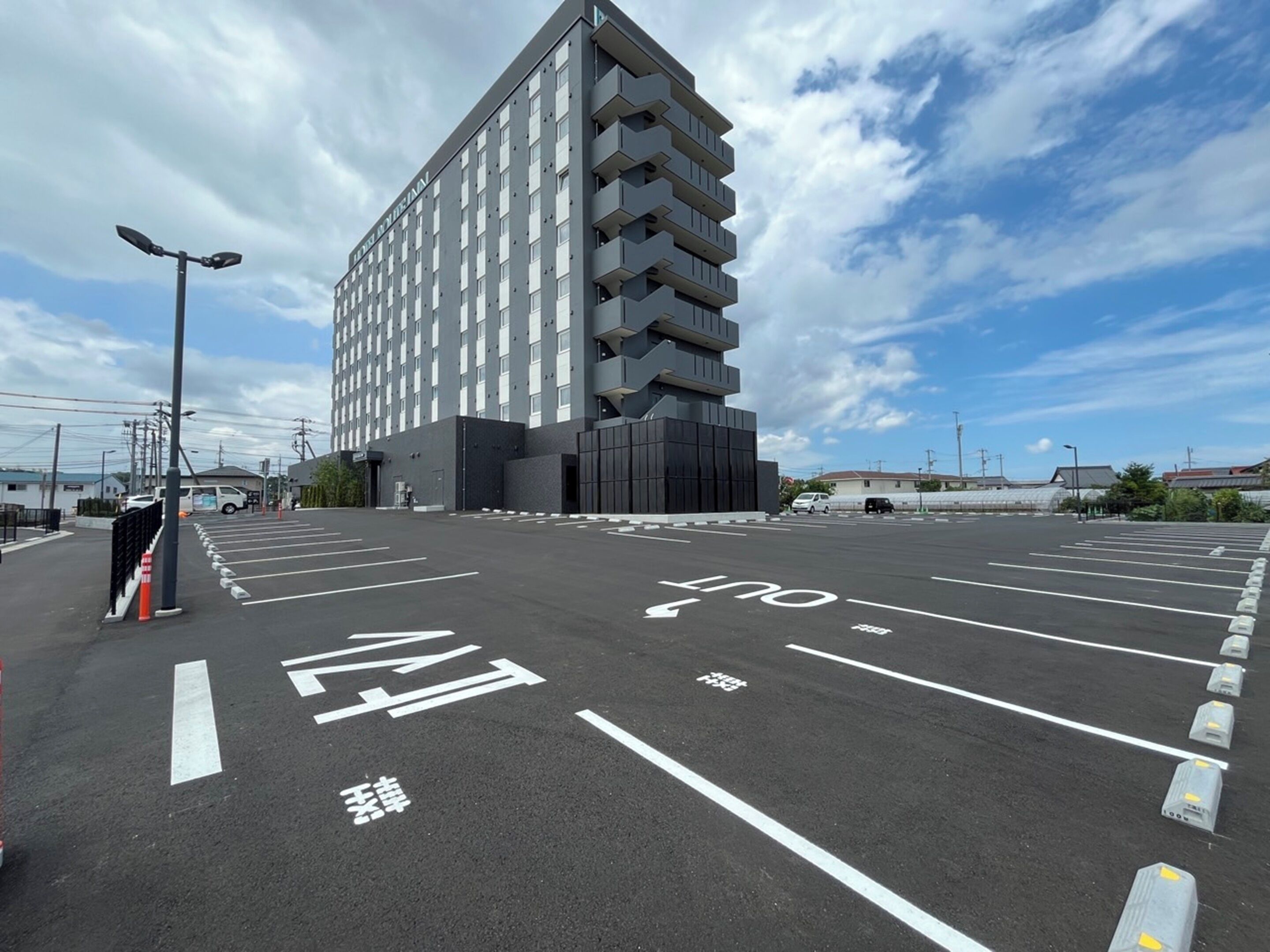 A modern multi-story hotel with a parking lot in front.