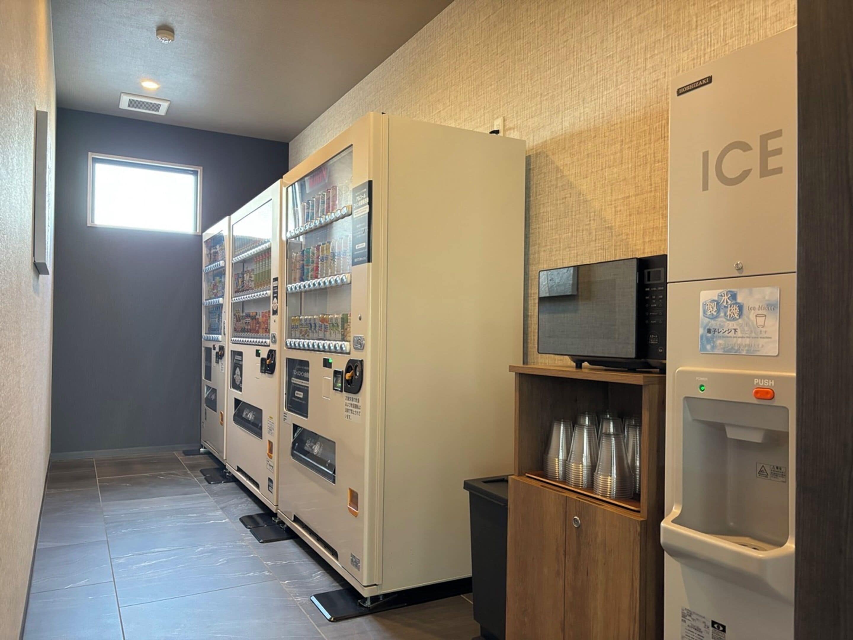 Ein Flur mit Getränkeautomaten und einem an der Wand befestigten Kühlschrank, auf dem 'ICE' steht.