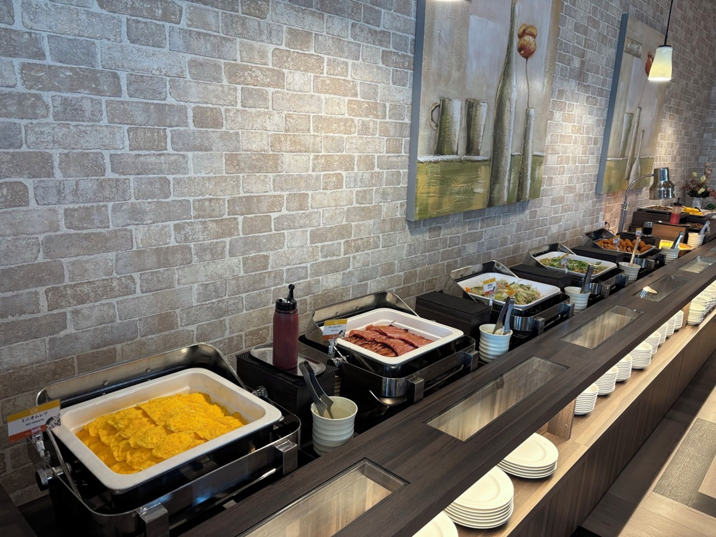A buffet with various food options, including a large container of yellow rice, a dish of red meat, and several other dishes.