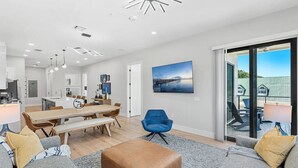 Un salon moderne comprenant un canapé, un pouf et un coin repas avec une table et des chaises.