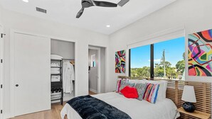Une chambre moderne avec un grand lit, un dressing et une vue sur l’extérieur.