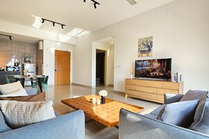 Una sala de estar moderna con una mesa de centro de madera, sofás grises y un televisor sobre un mueble de madera.