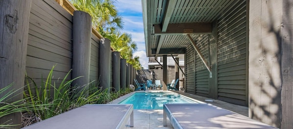 A pool area with lounge chairs and a wooden fence. - Pelican Bluff, a premier beachside home. Private pool and elevator by Kaiser Vacations (Orange Beach)