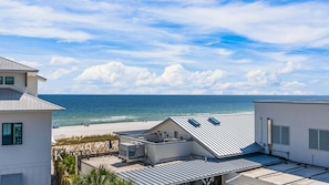Ein Küstenanwesen mit Blick auf den Strand, ein Dach mit Solaranlagen und einem wolkenlosen Himmel.