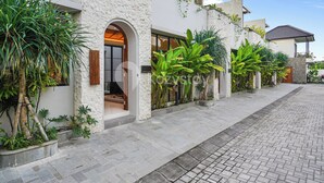 A modern house with a stone facade, large windows, and a paved driveway. - Lucenta Villa by Kozystay - Canggu (Canggu)
