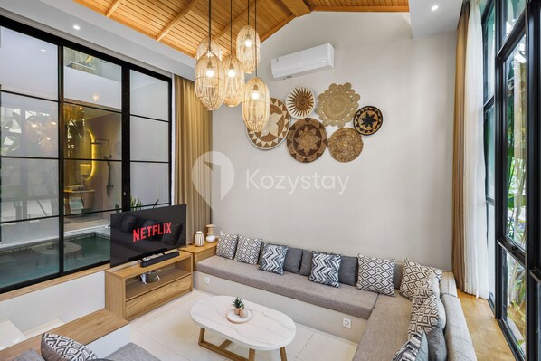 Un soggiorno moderno con un divano, un tavolino da caffè e una TV che mostra 'NETFLIX'.