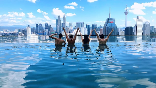 A group of people in a rooftop infinity pool with a city skyline in the background. - Maison 101 Residence walk to Menara KL (Kuala Lumpur)