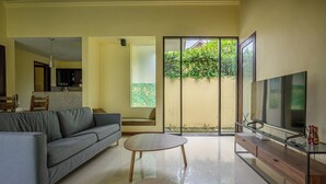 A modern living room with a grey sofa, a wooden coffee table, and a TV on a wooden stand.