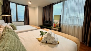 A hotel room with two beds, a TV, a view of the city, and a tray of towels. - Mercu Summer Suites KL Lifestyle (Kuala Lumpur)