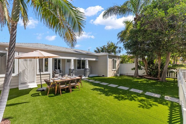 A residential property with a patio, outdoor seating, and a well-maintained lawn.
