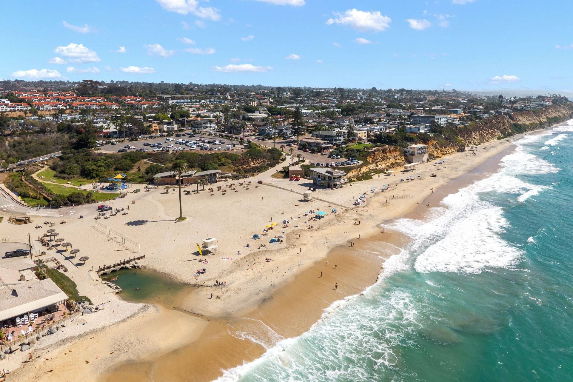 A coastal town with a beach, buildings, and a clear sky.