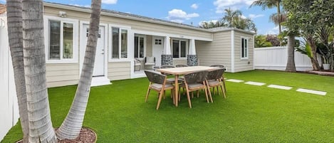 A residential property with a well-maintained lawn, a dining area with a table and chairs, and a white house with a number 719 on the door.