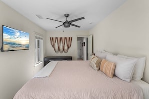 A bedroom with a bed, a ceiling fan, a TV on the wall, and a view of the outdoors. - Walk to Moonlight Beach, Updated and Remodeled, Dream Getaway (Encinitas)