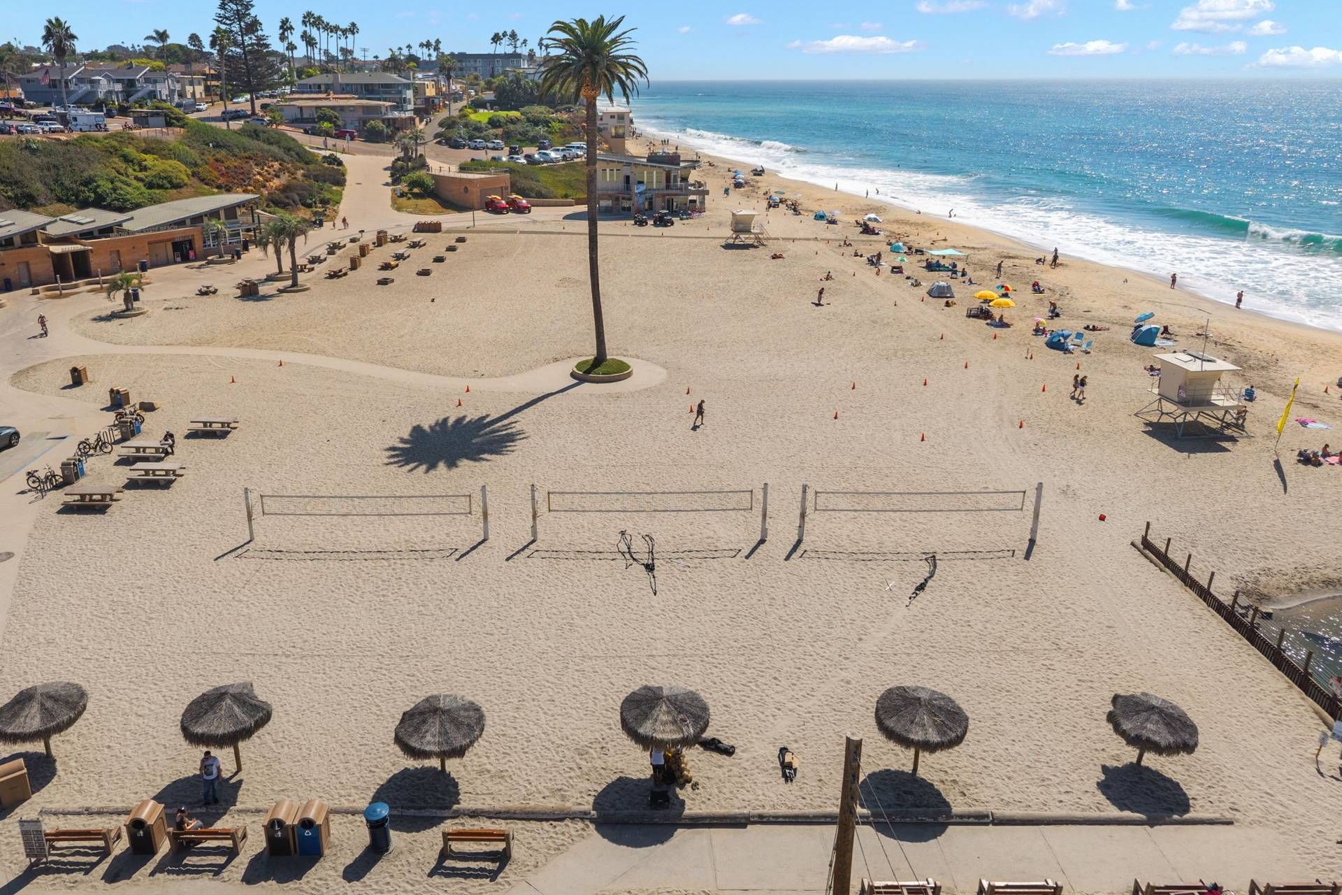Une plage avec un terrain de volley-ball, des parasols et des chaises de plage.