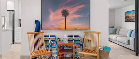 A dining area with a wooden table, two chairs, and a colorful striped bag.
