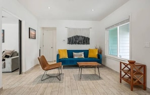 Ein Wohnzimmer mit einem blauen Sofa, einem braunen Sessel, einem Holztisch und einem kleinen Beistelltisch.