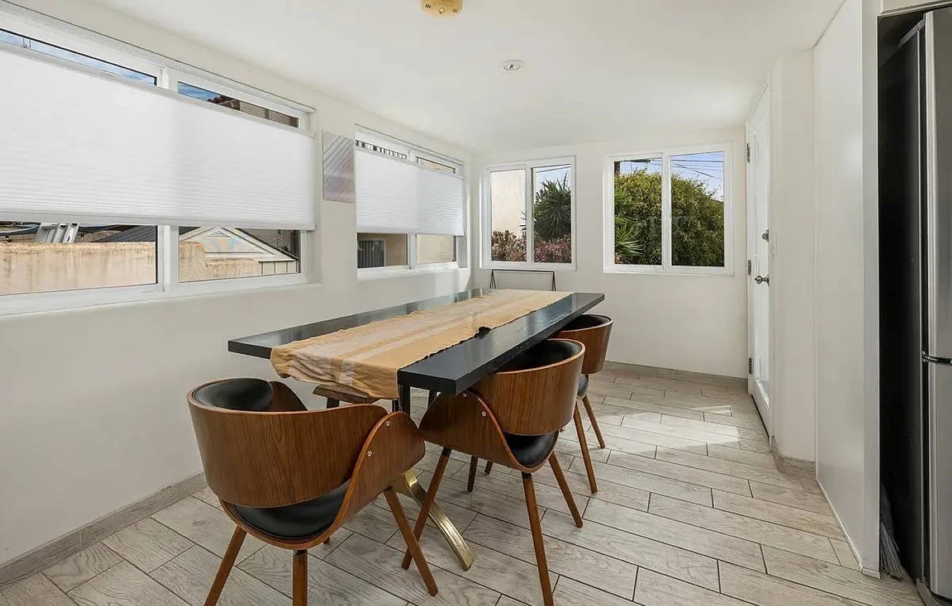 A modern kitchen with a dining table, four chairs, and a refrigerator.