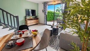 Un salon moderne comprenant un coin repas, un téléviseur et une vue sur l’extérieur.