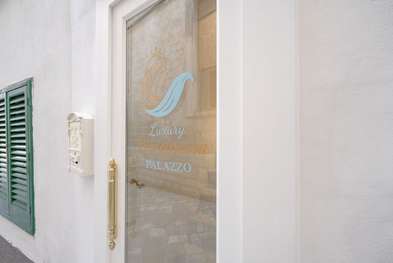 En byggnadsentré med en glasdörr som har en logotyp och texten ”Luxury Principessa Palazzo”.