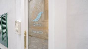 En byggnadsentré med en glasdörr som har en logotyp och texten ”Luxury Principessa Palazzo”.