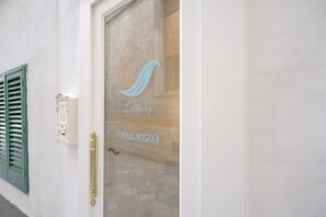 Une entrée d’immeuble dotée d’une porte en verre sur laquelle figure un logo et l’inscription « Luxury Principessa Palazzo ».
