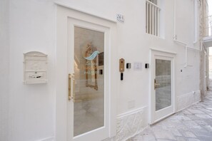 Un bâtiment blanc avec une porte en verre, une boîte aux lettres et un panneau indiquant le numéro.