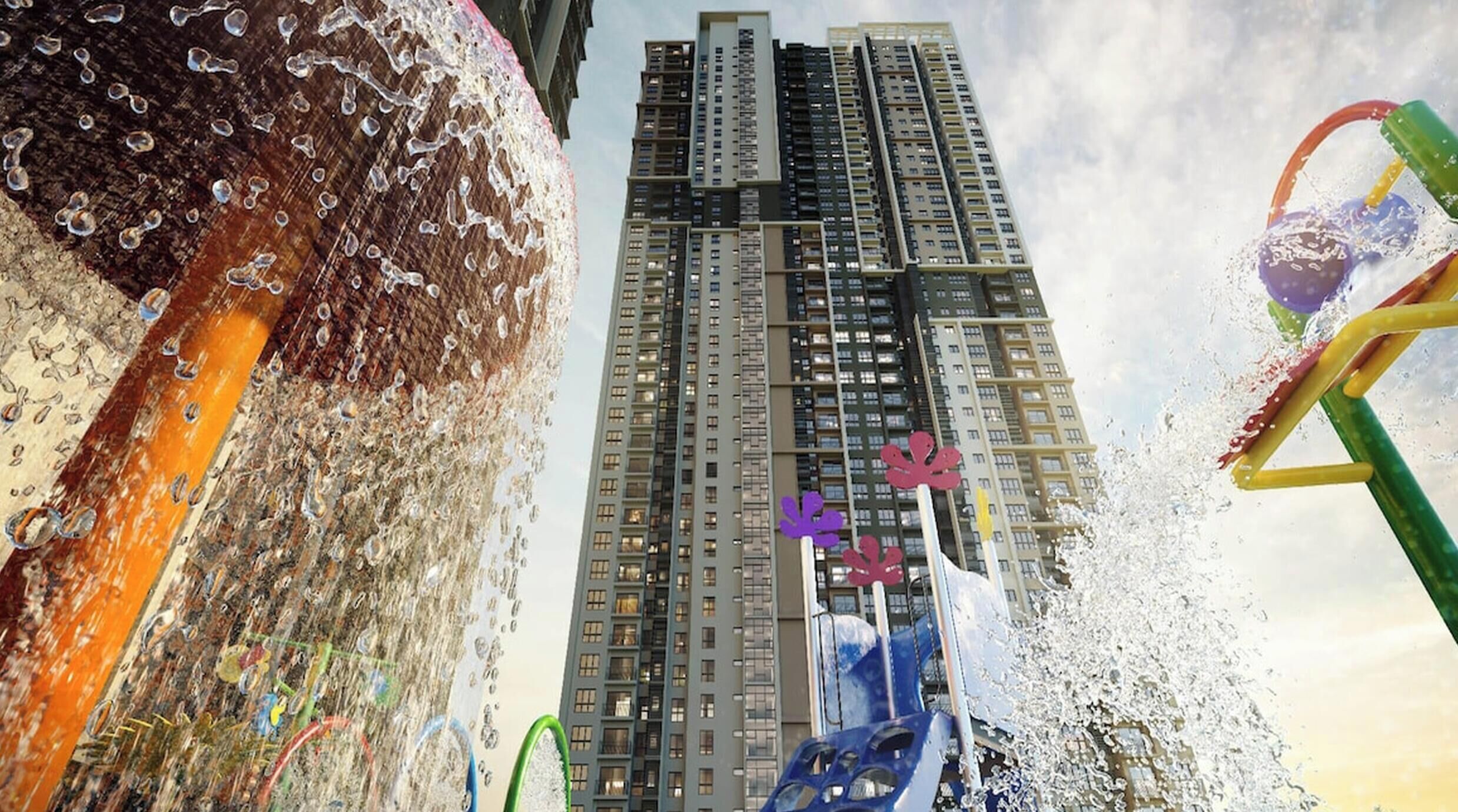 A water play area with a slide and climbing structure, set against a backdrop of tall residential buildings.