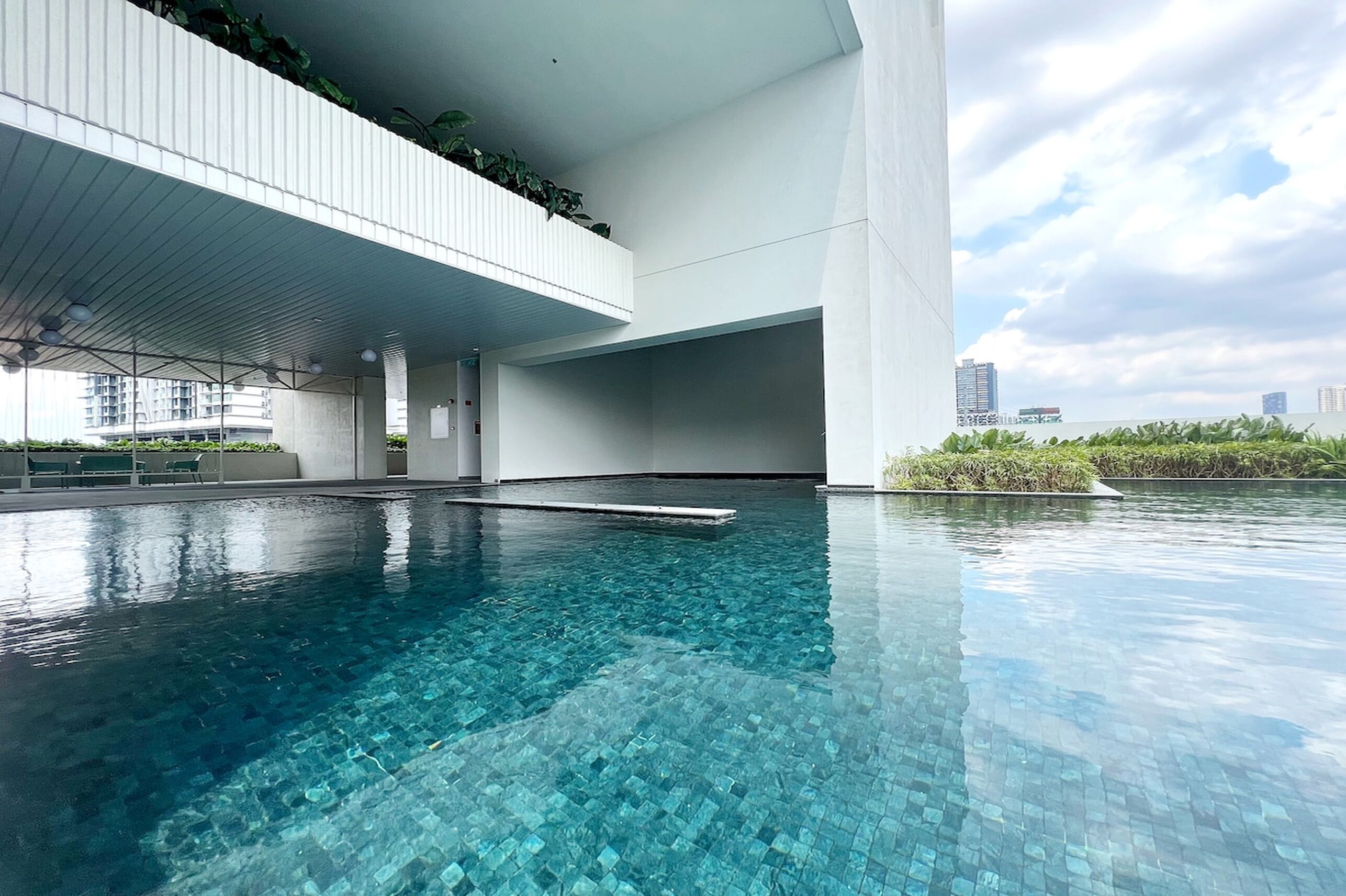 A modern indoor swimming pool with clear blue water, surrounded by white walls and a flat roof.