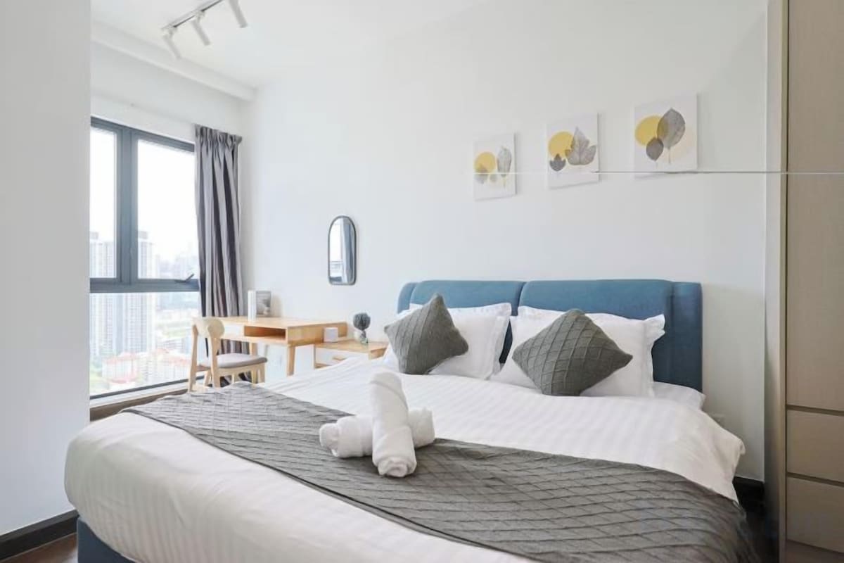 A hotel room with a bed, a desk, and a window.