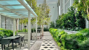 A covered outdoor area with a checkered floor, seating, and lush greenery. - Staycation V Residence - Sunway Velocity (Kuala Lumpur)